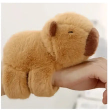 Bracelet peluche animal de 17 cm avec un capybara en peluche douce couleur tan aux oreilles et nez marron posé sur une main