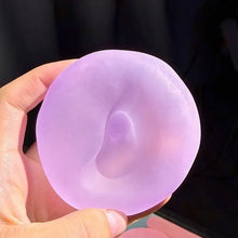 Main tenant une balle anti-stress squishy nacrée lavande en silicone translucide en forme de donut lisse