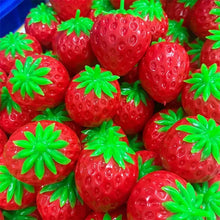 Balle sensorielle fraise en plastique rouge avec texture croquante et sommets feuillus verts pour presser
