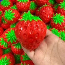 Balle sensorielle fraise en plastique rouge brillant avec texture croquante et feuillage vert pour presser