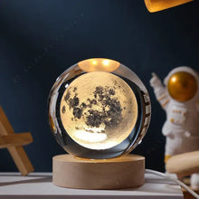 Lampe boule en verre gravé 3d de 5 cm avec surface lunaire noire et or sur socle bois élégant