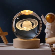 Lampe boule en verre gravé avec design saturne lumineux de 5 cm posée sur un socle bois clair