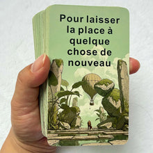 Une main tenant un jeu de cartes tarot français murmure cosmique avec illustrations artistiques pour réflexion personnelle des amateurs d’oracles