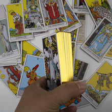 Une main tient un jeu de cartes rider tarot avec illustrations détaillées et bords dorés pour cartes tarots anglais the rider