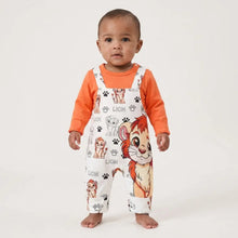 Combinaison bébé garçon blanc avec imprimé roi lion ludique et motifs pattes portée sur un t-shirt orange manches longues