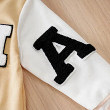 Patch lettre a blanche et noire sur manche beige et blanc de combinaison bébé garçon université style varsity