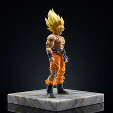 Figurine dbz super saiyan goku avec cheveux dorés et tenue orange et bleu sur socle en marbre poli