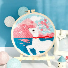 Kit de broderie punch needle présentant un cerf blanc coloré dans un cercle en bois avec motifs roses et bleus