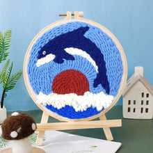 Kit de broderie punch needle avec orque bleue et blanche sautant devant un soleil rouge dans un cercle en bois