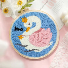 Kit de broderie punch needle avec motif cygne blanc rose et couronne jaune brodé sur fond bleu dans un cercle en bois