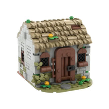 Jeu de construction maison médiévale en briques beige et marron avec toit de chaume et fenêtres arquées verts
