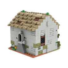 Détail d’une construction maison médiévale en briques lego beige et blanc avec toit en tuiles et fenêtres à croisillons