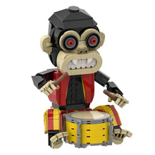 Lego singe d’horreur batteur en tenue rouge et noir tenant baguettes devant batterie jaune et grise jeu de construction singe 487 pièces