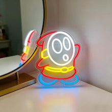Enseigne néon led shy guy USB représentant un personnage kirby en contours lumineux rouge jaune bleu avec un visage blanc