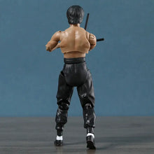 Figurine bruce lee legacy 50th en plastique noir d’homme musclé tenant deux nunchaku en pantalon noir et chaussettes blanches
