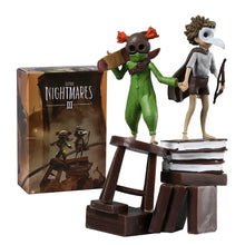 Figurine little nightmares iii low et alone avec deux personnages verts et marron sur des livres empilés