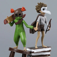 Figurine little nightmares iii personnage vert et marron avec tresses orange portant un masque et tenant un objet en bois