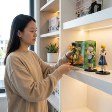 Figurines hunter x hunter vert et orange en pose dynamique sur socle d’exposition noir