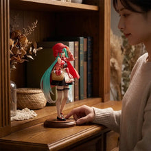 Figurine hatsune miku bandai 18 cm avec cheveux rouge et bleu, capuche rouge, jupe noire et panier beige sur socle bois