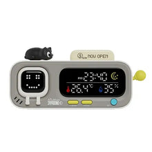 Horloge numérique de bureau grise avec affichage souriant, thermomètre, hygromètre, boutons jaunes et chat noir rechargeable