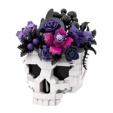 Vase lego moc crâne blanc orné de fleurs violettes, roses et noires dans le moc crâne roses