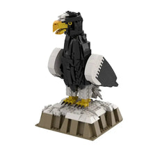 Lego moc oiseaux noir et blanc avec bec, pattes et yeux jaunes sur socle rocheux dans animaux volants