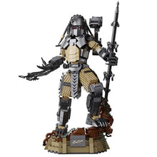 Lego moc predator alien en noir et brun avec armure détaillée, arme et mains griffues debout sur base rocheuse