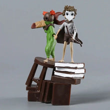 Deux figurines stylisées little nightmares iii sur un tabouret en bois posé sur des livres empilés, hauteur 11 cm