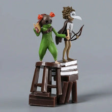 Figurines green and brown from little nightmares iii standing on a wooden stool atop stacked books 11 cm tall