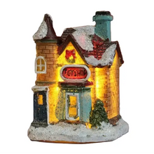 Maisonnette lumineuse de noël miniature à piles en façade jaune avec toit rouge enneigé et fenêtres éclairées