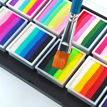Maquillage palette arc-en-ciel 12 couleurs avec palette arc-en-ciel soluble et pinceau à manche bleu posé sur une palette