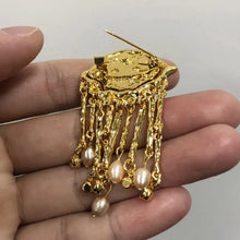 Broche œil mystérieux en métal doré avec top circulaire texturé et pampilles perlées idéale pour tenue halloween