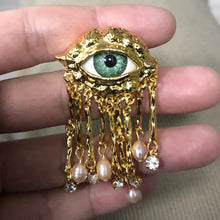 Broche œil mystérieux en ton or avec iris vert et pampilles perlées pour tenue halloween élégante