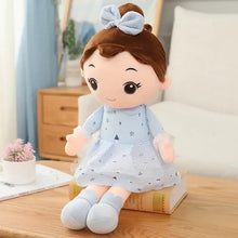 Peluche douce fille japonaise avec cheveux bruns en chignon, noeud bleu clair, robe bleue à motifs géométriques noirs