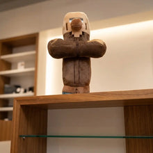 Peluche personnage villageois en beige avec casque et corps marron au design pixelisé inspiré de minecraft