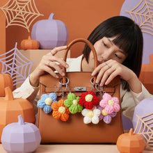 Porte clés fleur tricotée avec charms fleurs colorées accroché à un sac à main en cuir marron