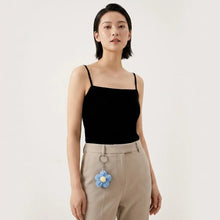 Porte-clés fleur tricotée délicate bleu avec centre jaune suspendue à la boucle d une ceinture beige