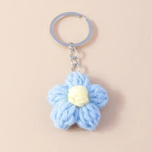 Porte-clés fleur tricotée délicate en bleu clair avec centre jaune pâle attachée à anneau et chaîne métallique argentés
