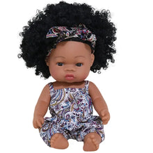 Poupon reborn à peau foncée en vinyle 35 cm avec afro bouclée, portant un romper paisley violet bleu blanc et bandeau assorti