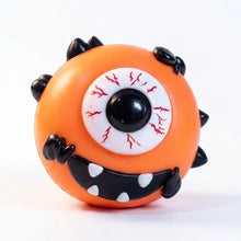 Squishy chien à visage interchangeable orange avec un œil unique, veines rouges, piquants noirs et bouche souriante
