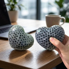 Une paire de squishy anti-stress cœur gris mat à texture à points noirs pour soulager le stress au quotidien