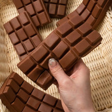 Une main tient un squishy chocolat anti stress en silicone marron avec effet slow rising et texture quadrillée