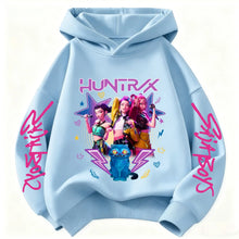 Sweat à capuche enfant bleu clair avec motifs colorés de chasseuses fantastiques et texte rose graffiti aux manches