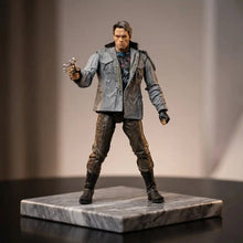 Figurine terminator t-800 de schwarzenegger en plastique gris et marron en tenue tactique posée avec pistolet sur socle marbre