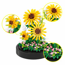 Une tournesol en briques plastiques jaune vif avec centre brun détaille éclairé par led à lumière chaude sous cloche transparente
