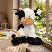 Vache en peluche douce noire et blanche avec museau beige assise sur un rebord de fenêtre compagnon sourire